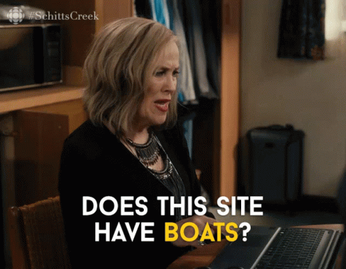 Moira from Schitt's Creek sits in front of a computer. She asks, "Does this site have boats?"